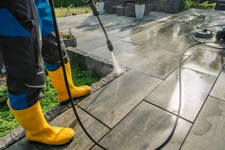 Worker pressure washing a driveway with professional equipment on a sunny day